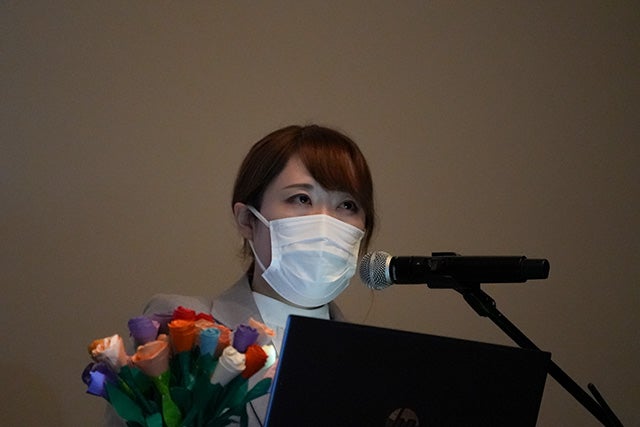 お客様からいただいた折り紙の花束とともに発表する霜鳥さん